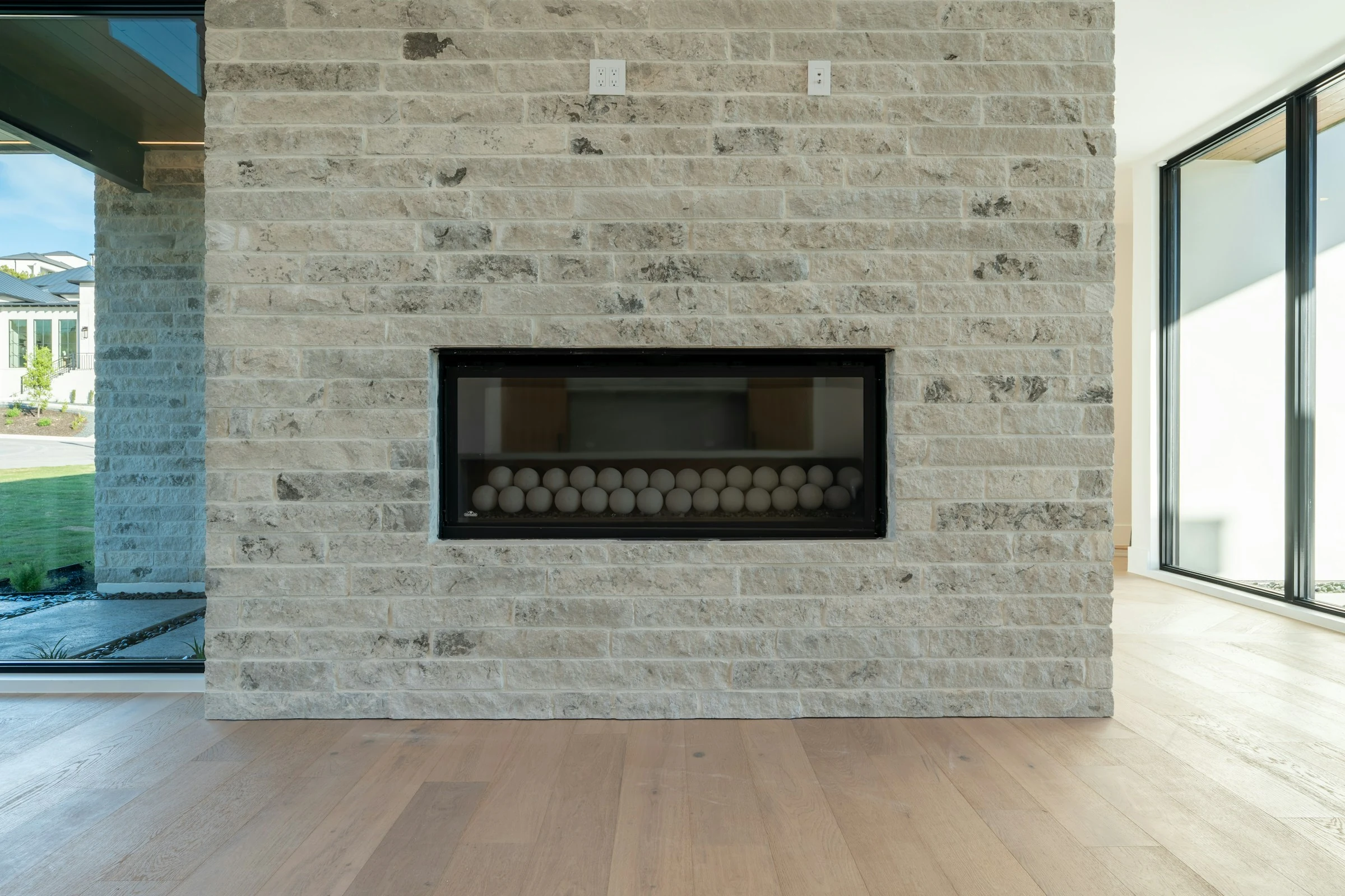 Contemporary glass-front fireplace set into a light brick wall